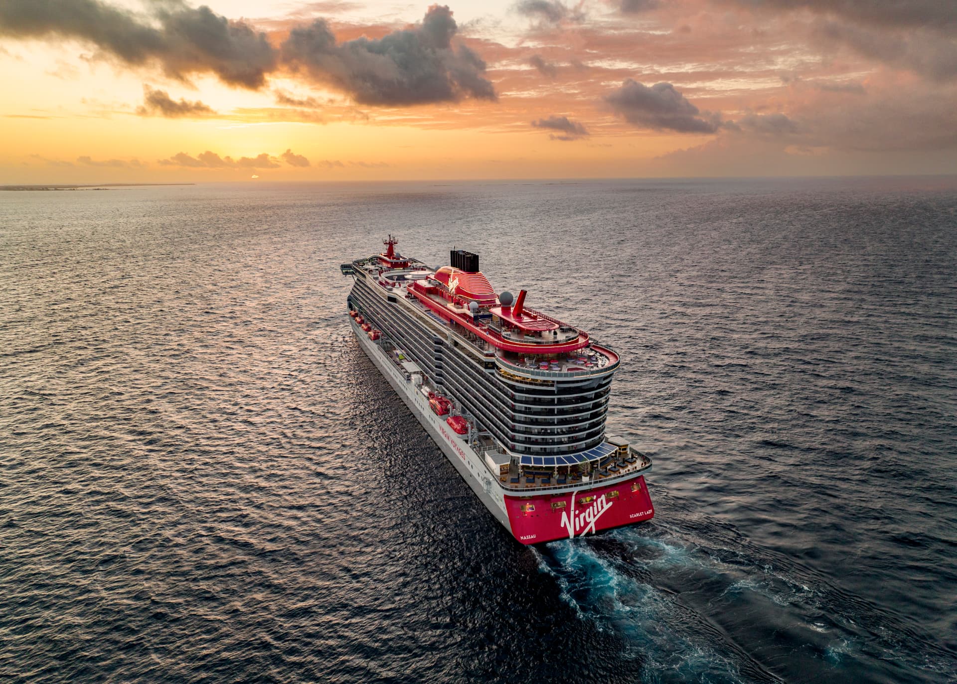 Scarlet Lady sailing away at sunset, viewed from behind